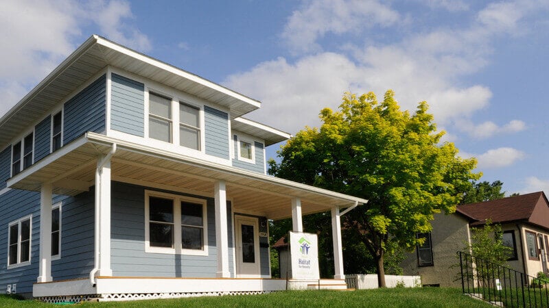 A blue Habitat home sitting on a small hill.