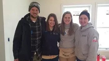 AmeriCorps members posing for a photo in an in-progress house.