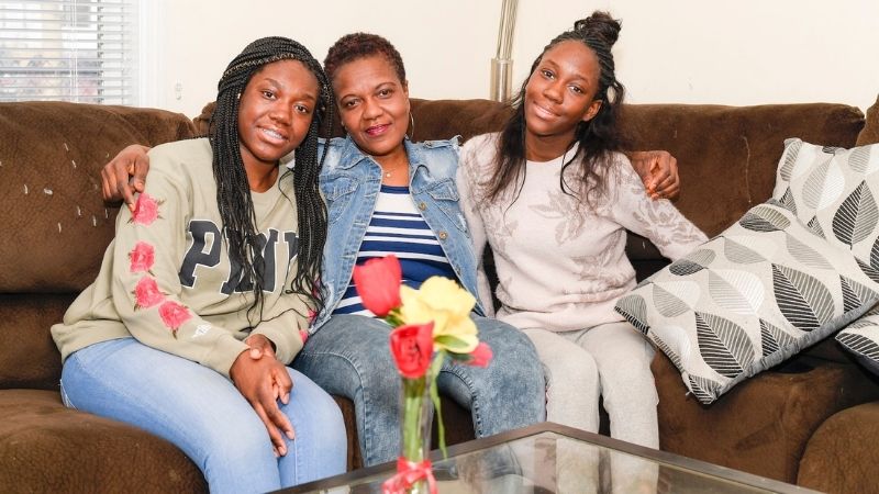 A Habitat homeowner sitting on a couch with her two children.