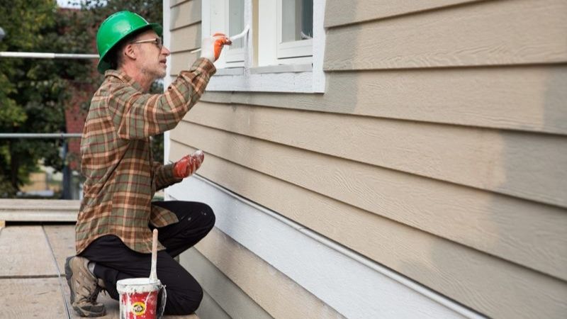 A volunteer painting the trim on windows.