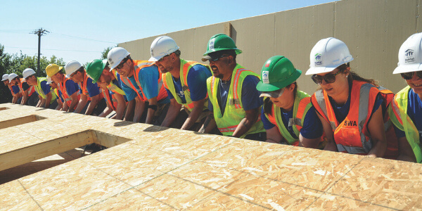 A group of volunteers working together to raise a wall.