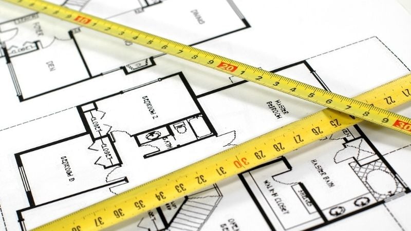 A drawing of the layout and square footage of a house, with tape measures laid on top.