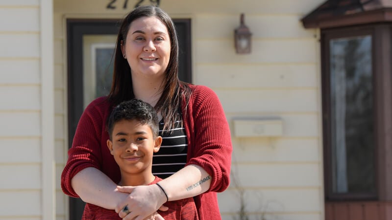 Brittany and her son Ayden in front of their Habitat home