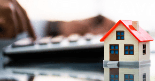 A tiny home in front of a calculator with blurred background