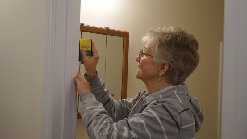 Marilyn painting a doorframe.