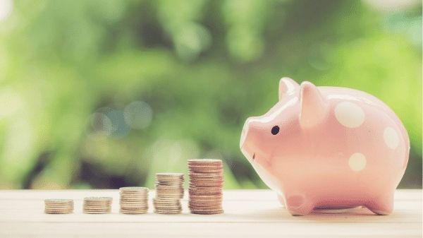 A pink piggy bank with stacks of dimes, nickels, and quarters by its nose. 