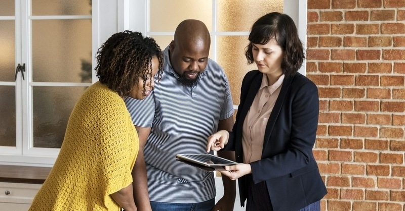 A couple looking at a tablet with a Realtor.