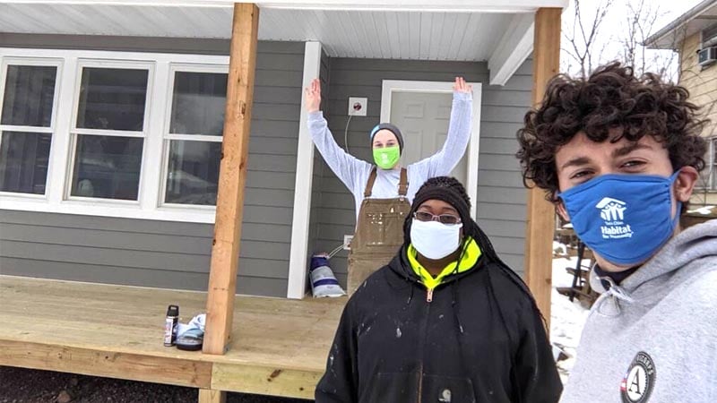 Image of a site supervisor and AmeriCorps service members on a front porch of a Habitat homebuilding site.