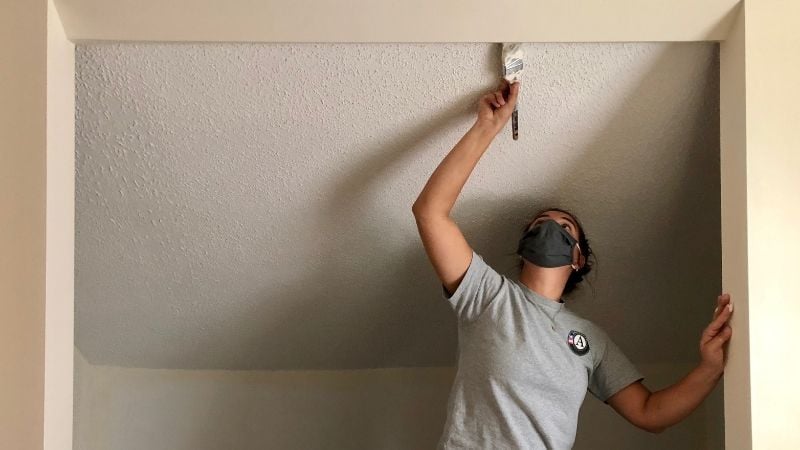 Maddie painting a doorframe at a Habitat home.