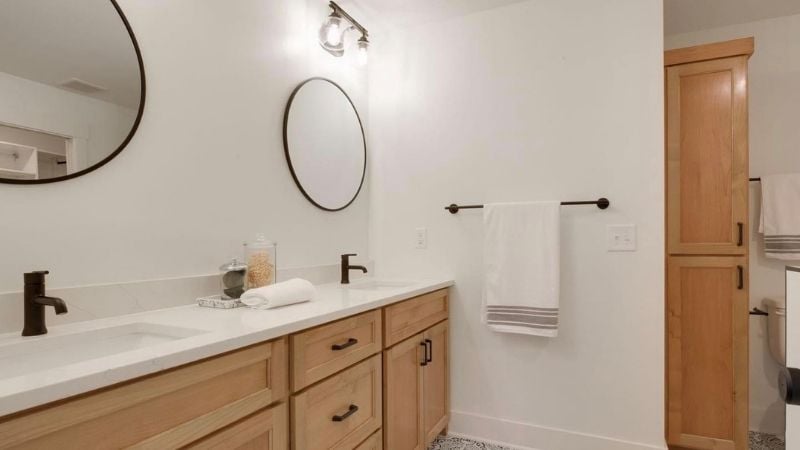 Updated bathroom with light wood cabinets and bronze finishes.