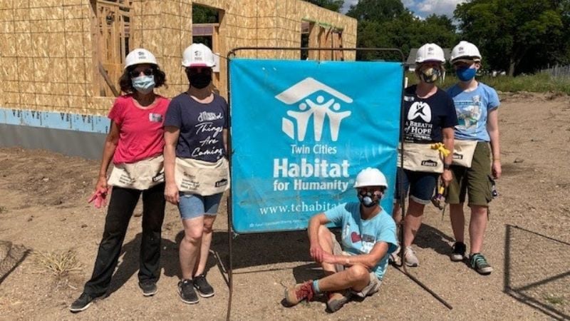 A group of volunteers sitting around a Habitat for Humanity banner.