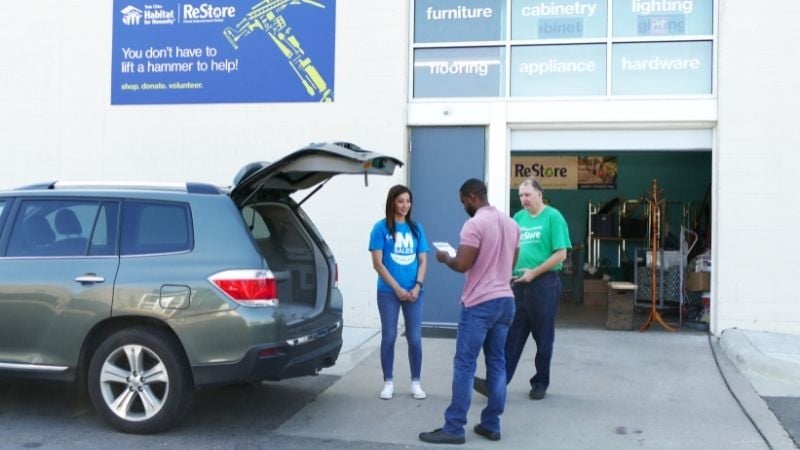 Three people standing outside of the back of a car donating to ReStore.