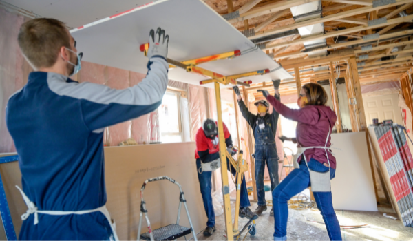 Volunteers lifting drywall