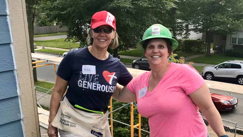 Nikki Sorum on a roof with her sister at a Habitat home build day.