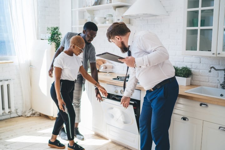 A realtor and buying couple inspecting a kitchen