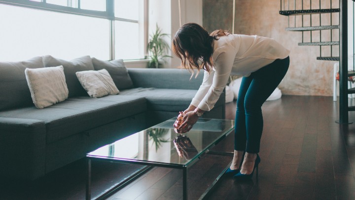 Woman arranging décor in a living room.