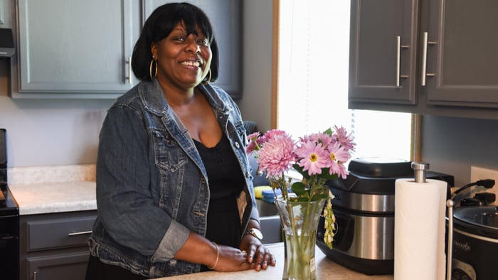 Angela standing in her kitchen next to a vase of flowers