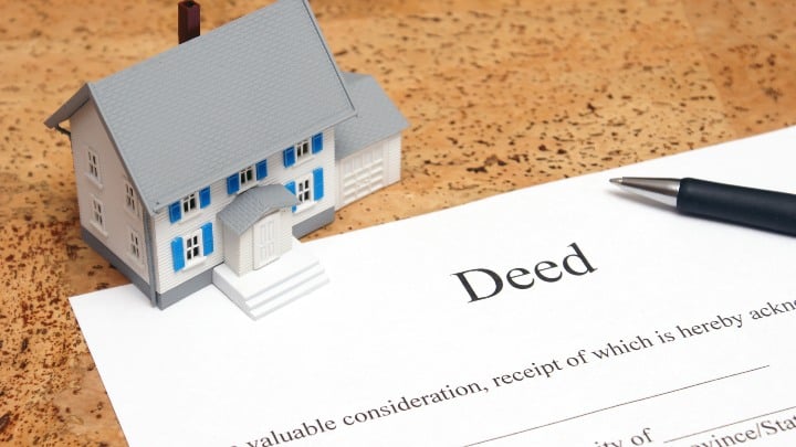 Image of a contract for deed paper with a miniature house as a paperweight.