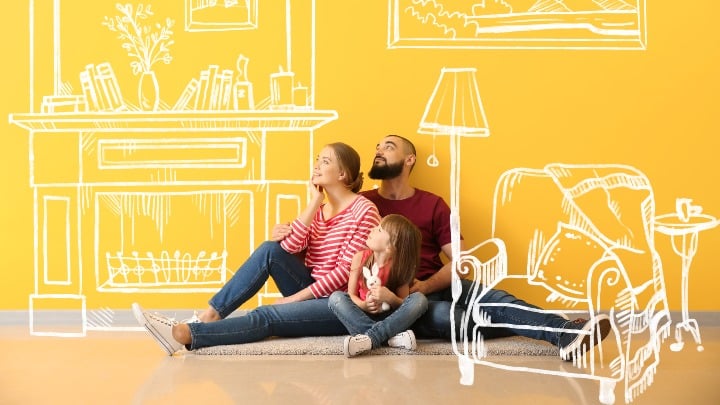 Young couple sitting on the floor of an empty room, dreaming of their home.