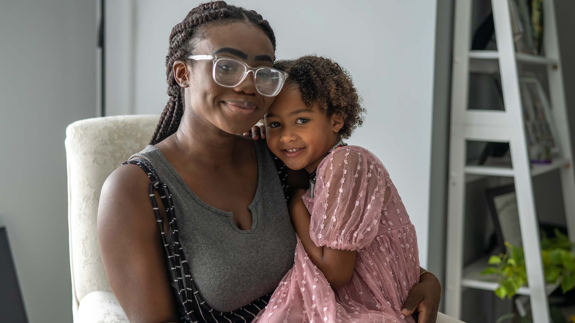 A woman holding her young daughter, both smiling