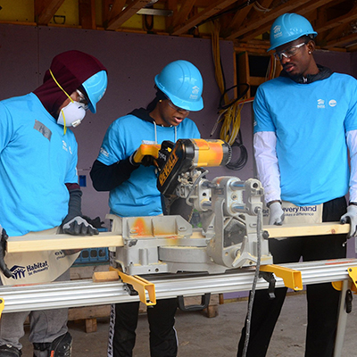 Three volunteers working near the saws on a build site.