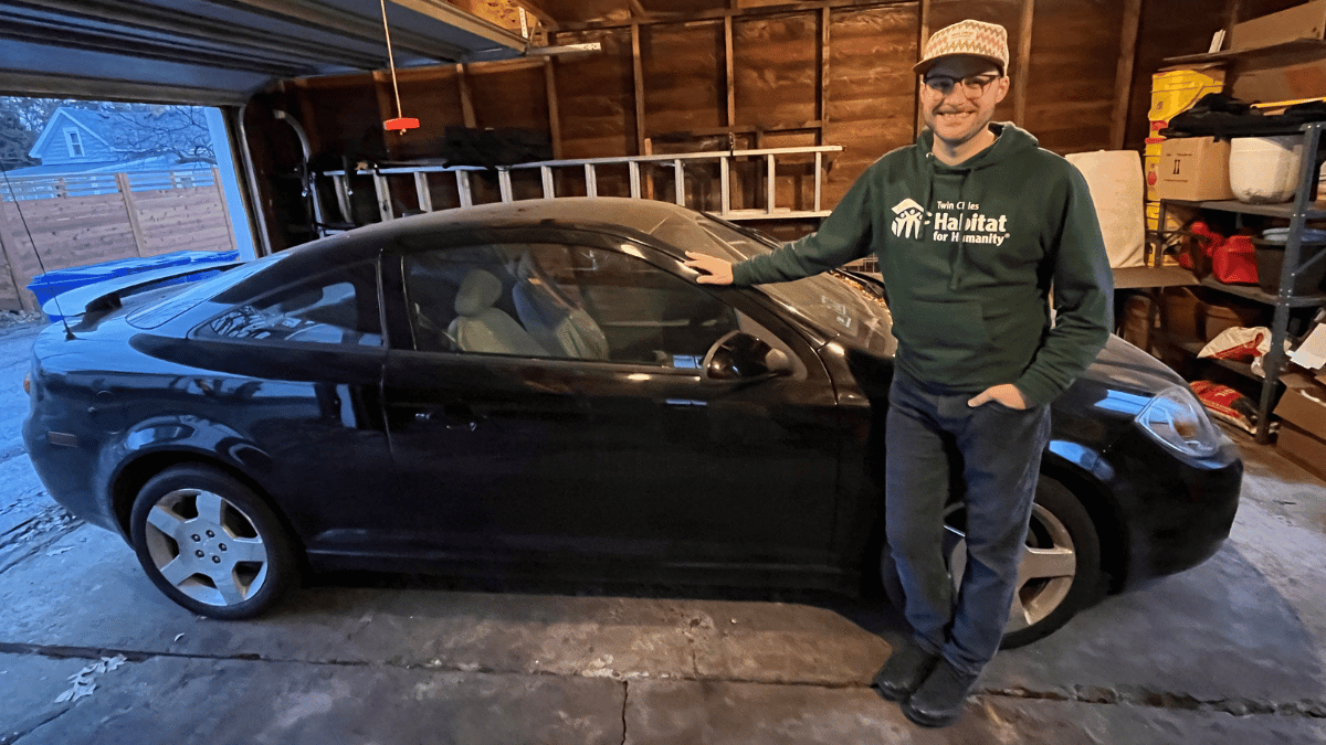 Greg standing in front of his black Chevy Cobalt