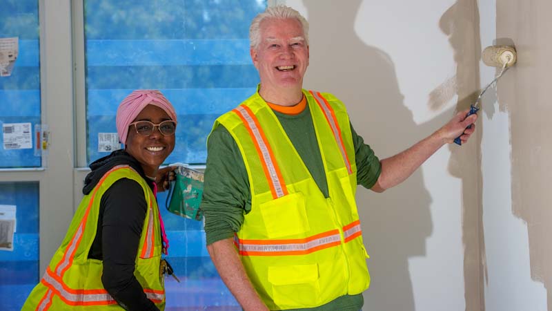 A man and a woman are smiling and painting together