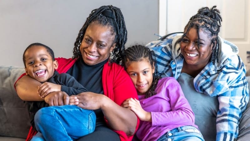 Arlisa and her three kids smiling and cuddling on the couch.