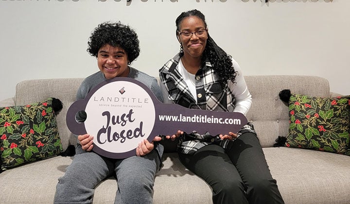 Asia and her child at their closing holding an oversized cardboard key