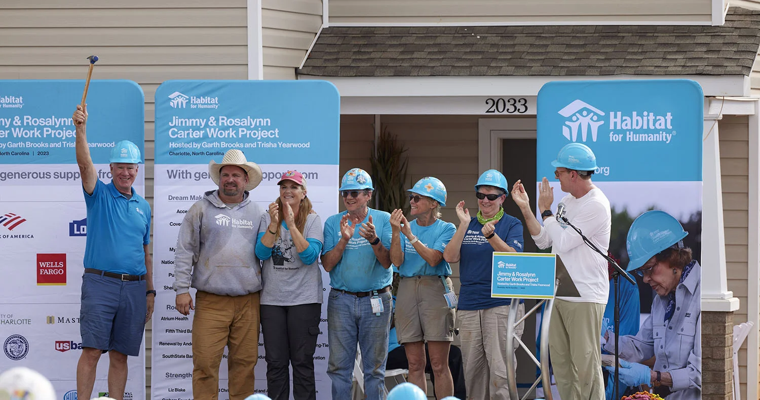 Jimmy Carter holding up a hammer next to volunteers at the 2010 Jimmy and Rosalynn Carter Work Project