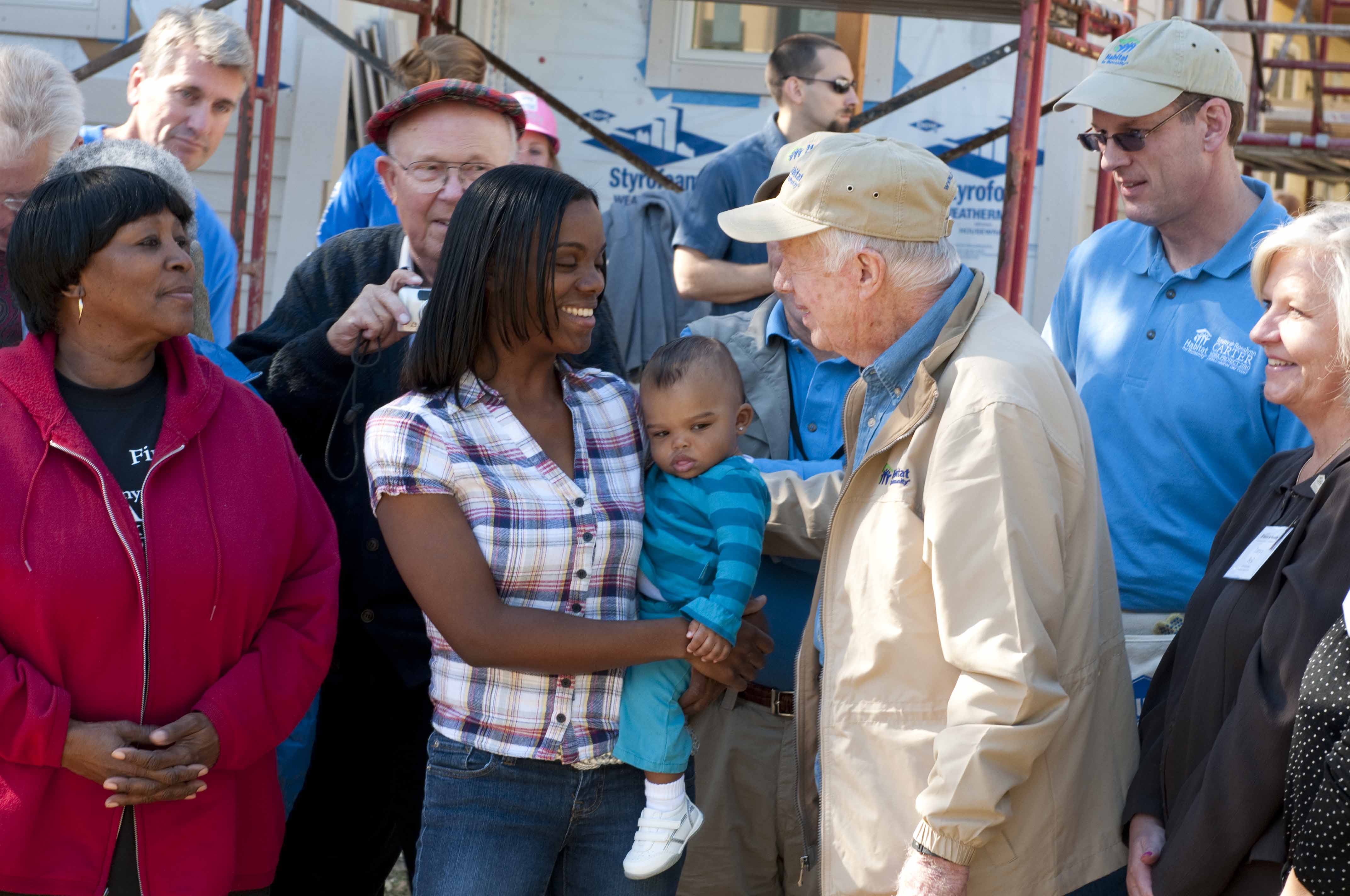 Jimmy Carter, a Habitat homeowner, and others stand and smile in a group