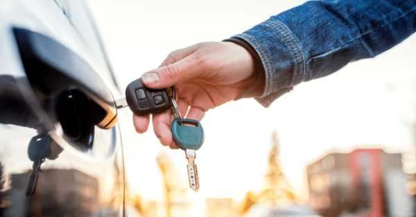 A person's hand putting a car key in a car door