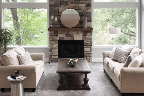 photo of a staged living room with two couches, a coffee table, in front of a fireplace