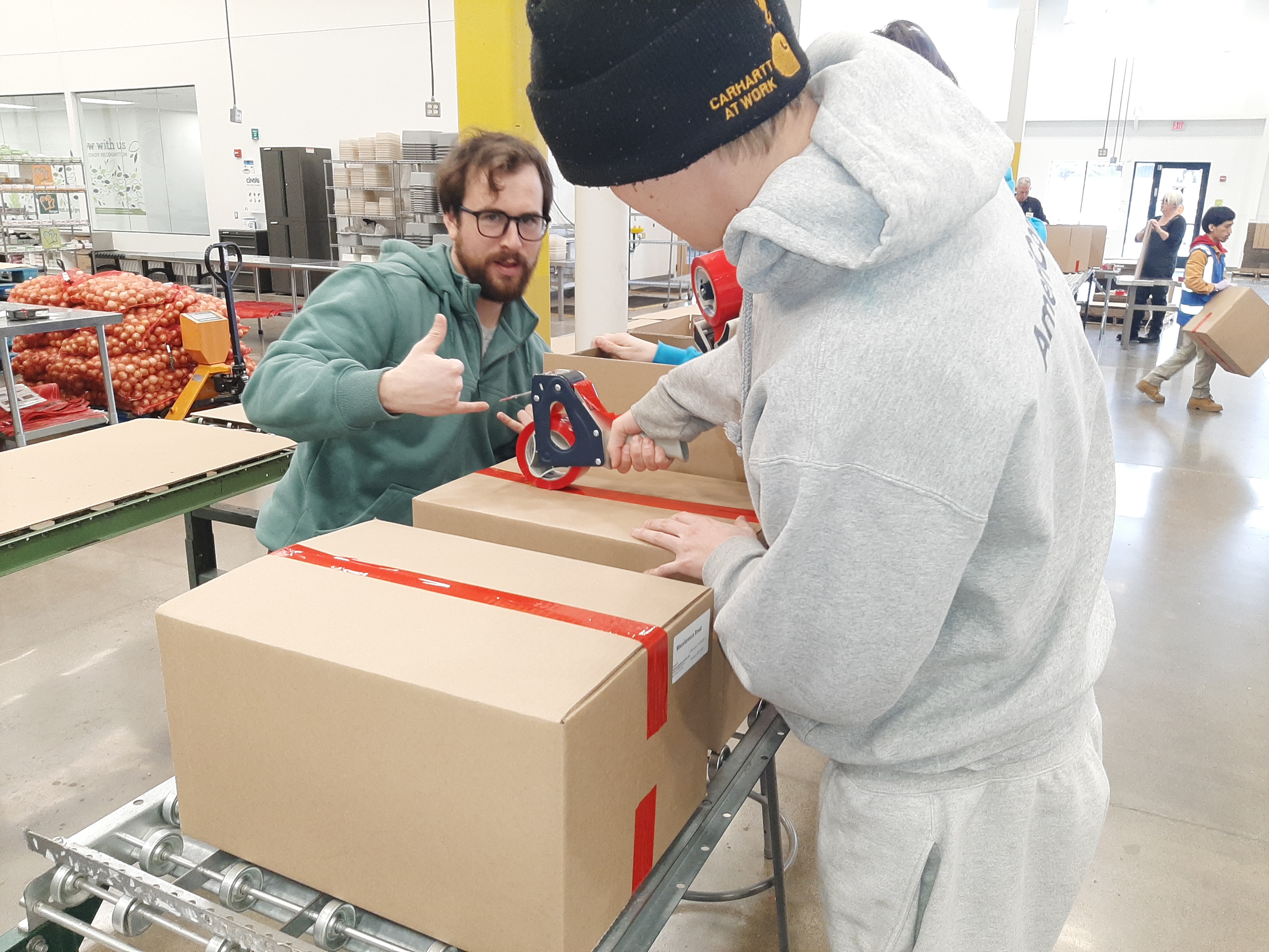 2 AmeriCorps Members Sealing up a box of repackaged bread so it can be loaded up onto the trucks. 