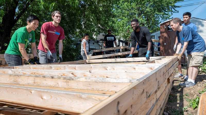 Twin Cities Habitat for Humanity volunteers prepare to lift a wall at a Habitat build site.