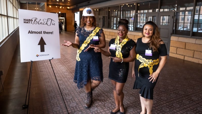 Three volunteers in nice black dresses showing the way to the gala.