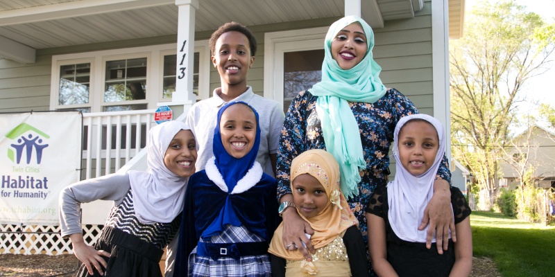 Habitat homeowner posing with her children in front of her house