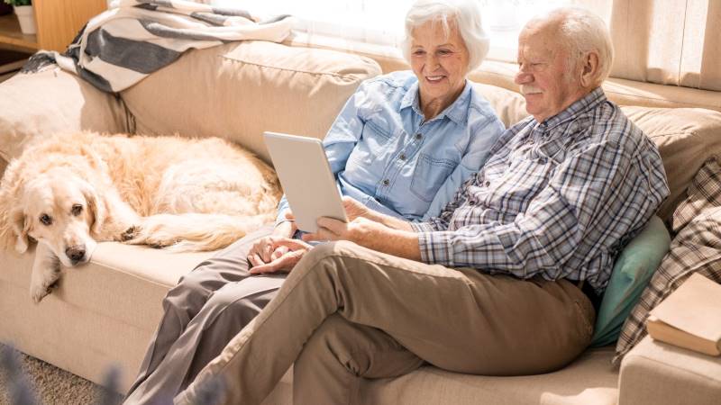 Health Implications of Moving as a Senior - husband and wife using tablet on couch – TC Habitat