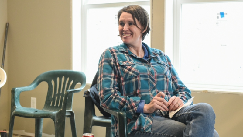 Jenny sitting in a chair and smiling at someone off camera.