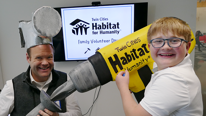 Jim Mulrooney (Left), and his son Mack Mulrooney (Right), posing with construction props at the Family Volunteer Day photo booth