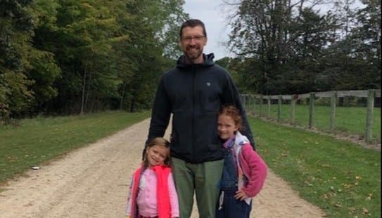An image of Ryan and his two kids on a country road.