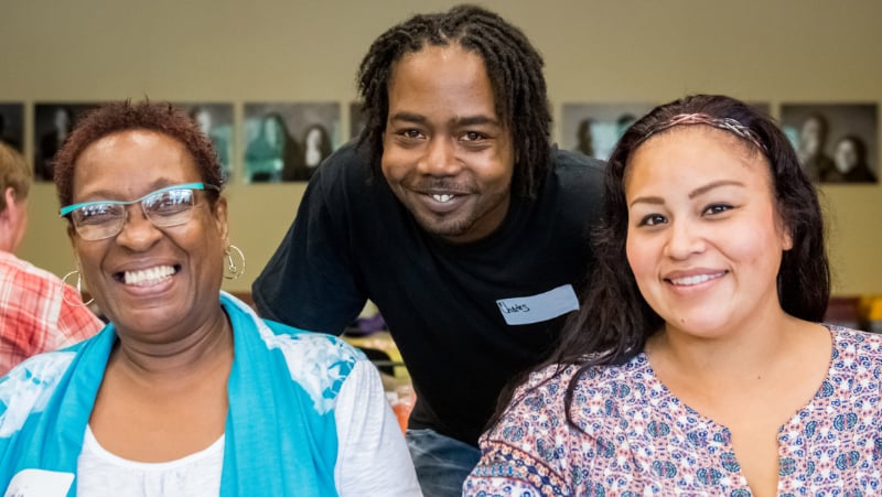 Two women and a man smiling.