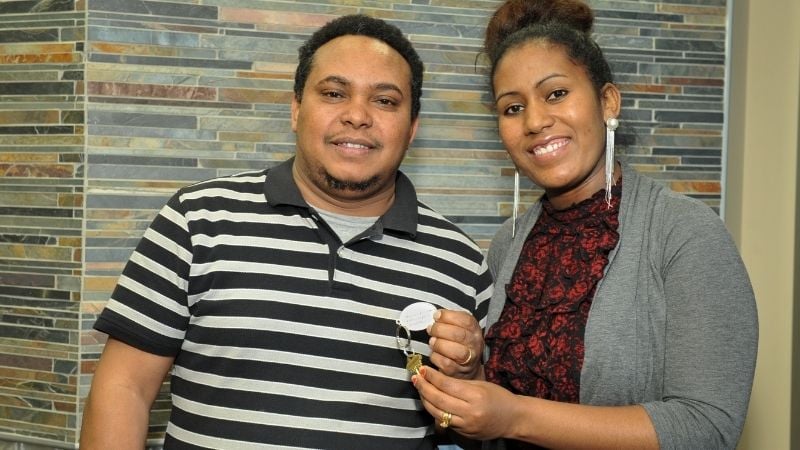 Two Habitat homeowners holding the keys to their new home.