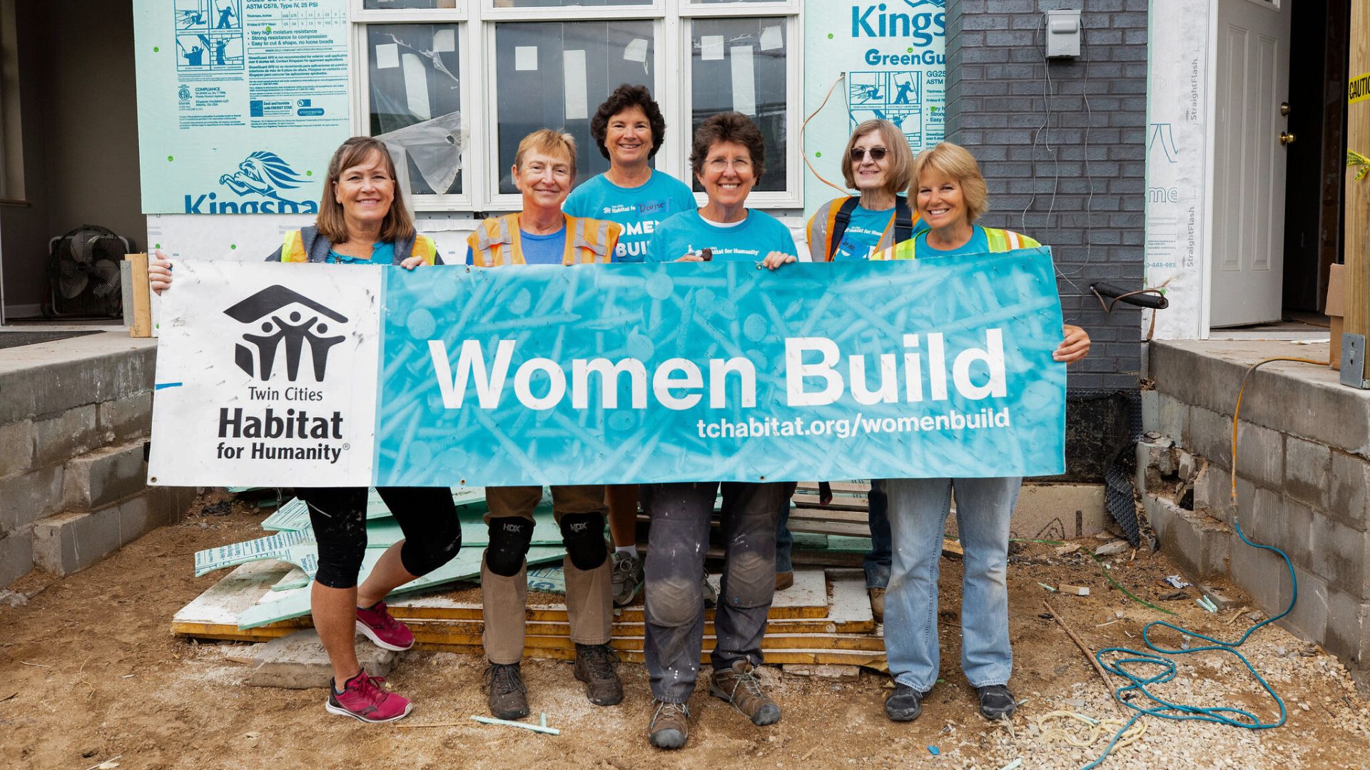 Women Build group smiling and holding banner.