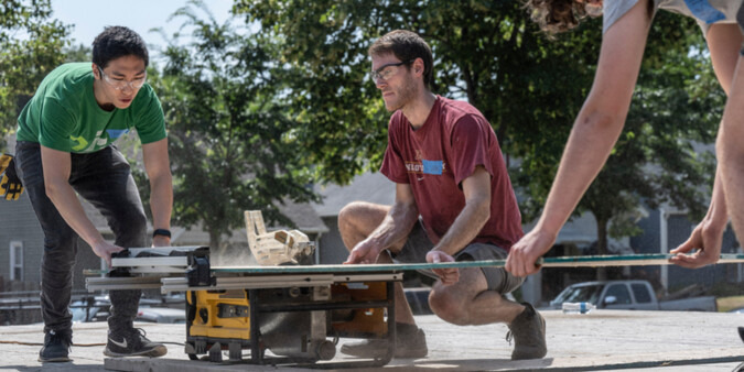 Volunteers sawing lumber.