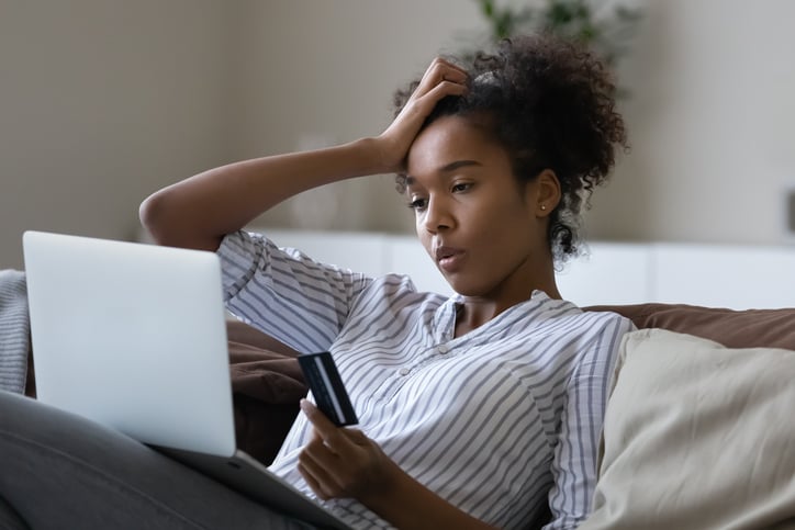 Woman looking at her laptop and holding a credit card.