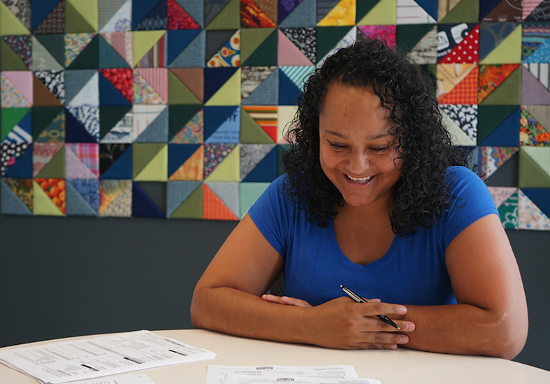 Woman smiling while reviewing homeownership documents.