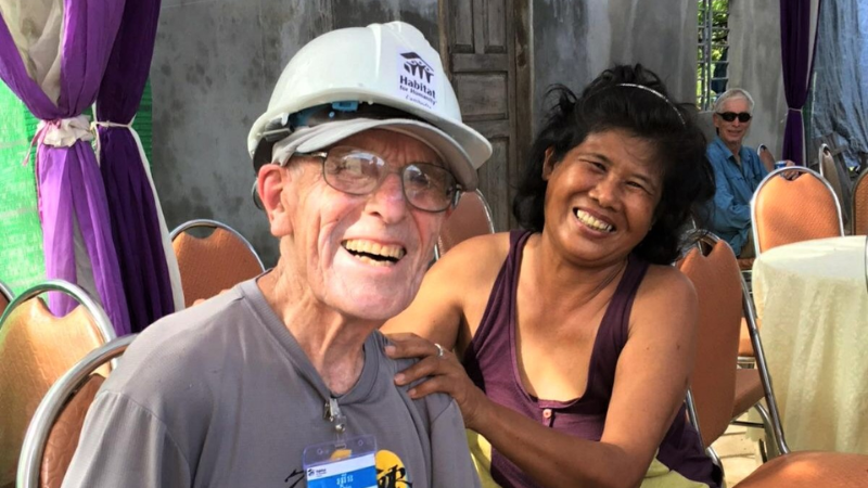 Orin in a hard hat smiling with a Cambodian woman.