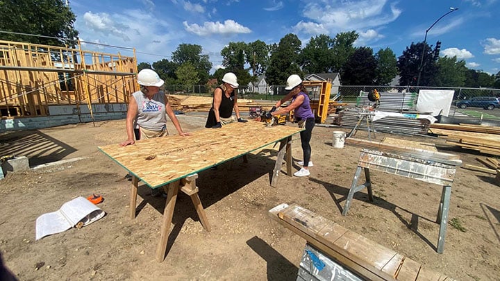 Volunteers using saws outside.